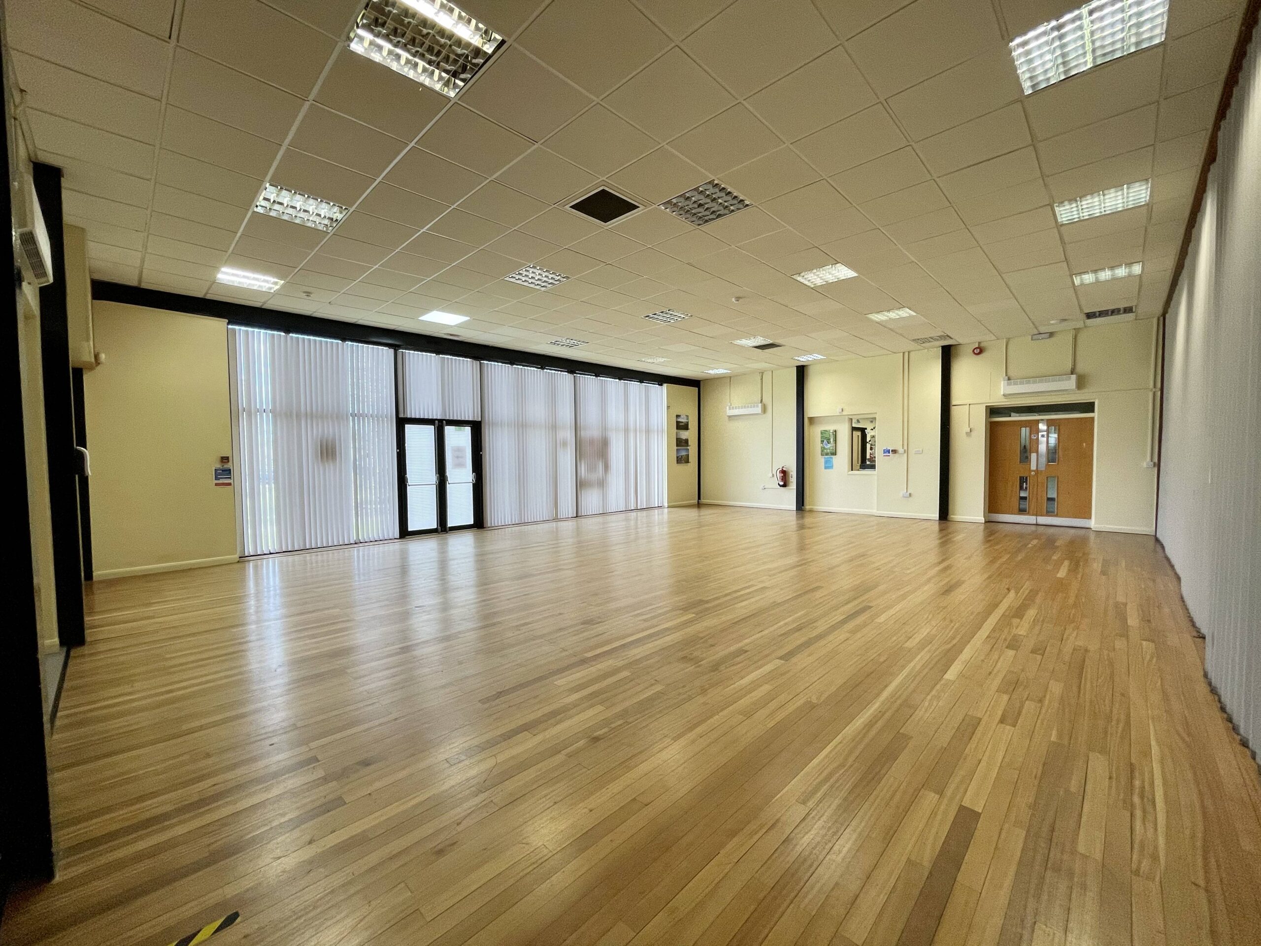 Large bright room with floor to ceiling window, wooden floor and cream walls.